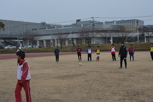 サッカー教室でグラウンドに立つ子どもたちと講師の写真