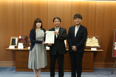 市長と委員が答申案を持って並ぶ様子