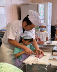 魚捌きを子供が体験する写真