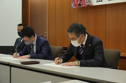 協定書に署名を行う澁江会長（左）と大久保市長（右）
