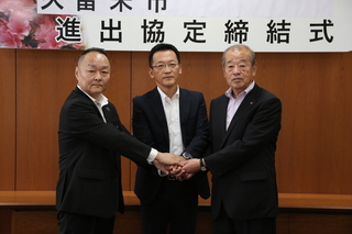 握手をする吉田社長、楢原市長、上川県企業立地課長の写真